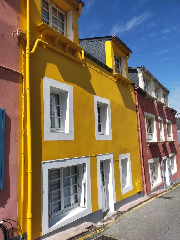un bâtiment jaune avec des fenêtres blanches sur une rue dans l'établissement Les 2 moi s'L, à Sauzon