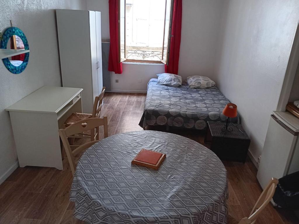 une petite chambre avec deux lits et une table dans l'établissement Studio intra-muros 5mn gare centre, à Avignon