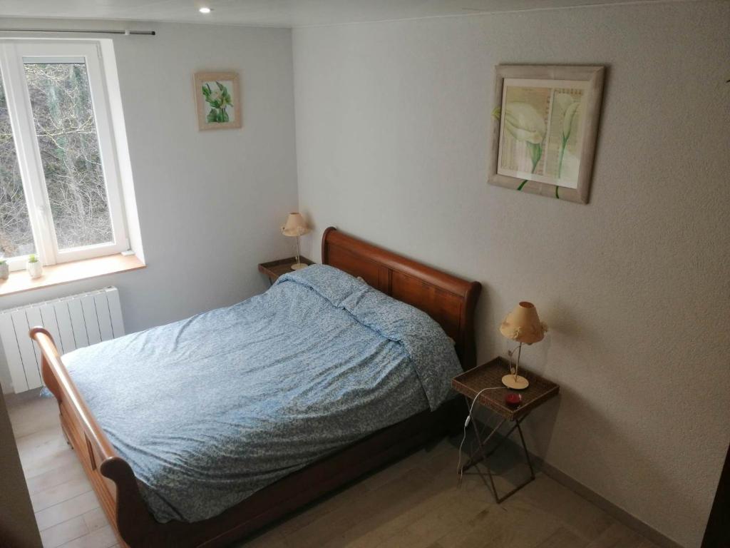 une chambre avec un lit et une table avec une lampe dans l'établissement Gîte calme bercé par le bruit du ruisseau, à Arinthod