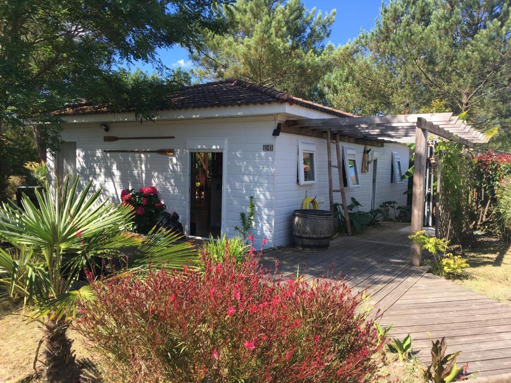Cette petite maison blanche dispose d'une terrasse couverte en bois. dans l'établissement LANDES CHALET 8 personnes, à Lit-et-Mixe