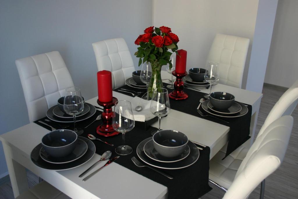 a dining room table with red roses on it at BTS Apartaments - Apartamenty Blisko Morza in Gdańsk