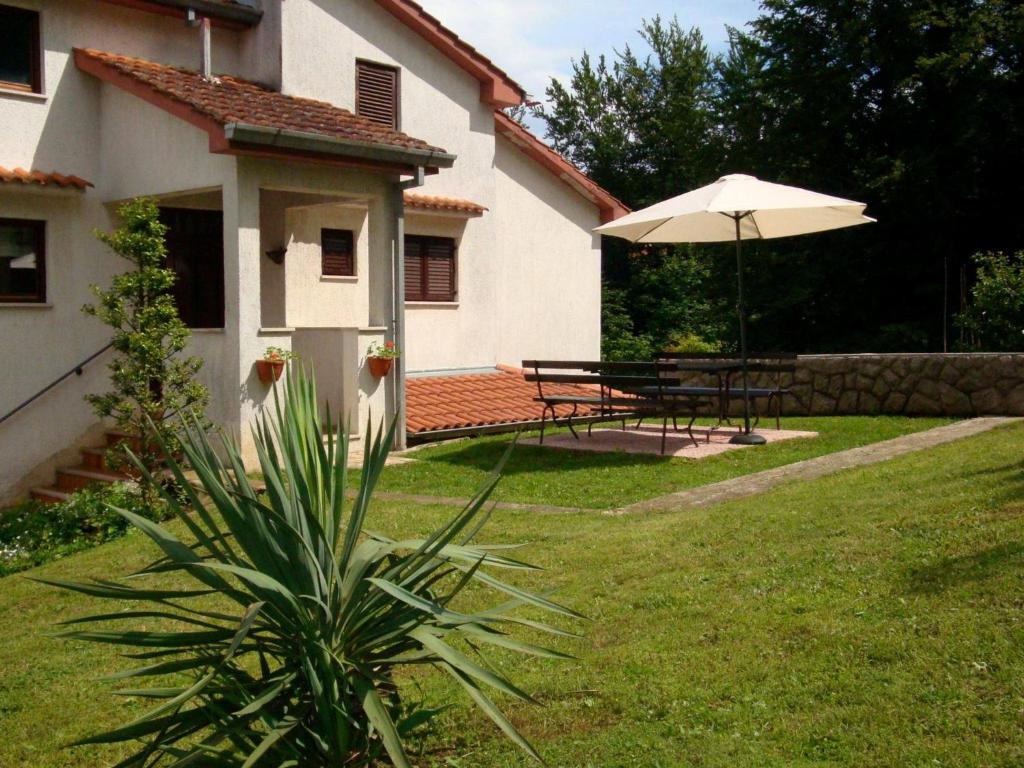 a garden with a table and an umbrella at Apartment Luno in Zvoneće