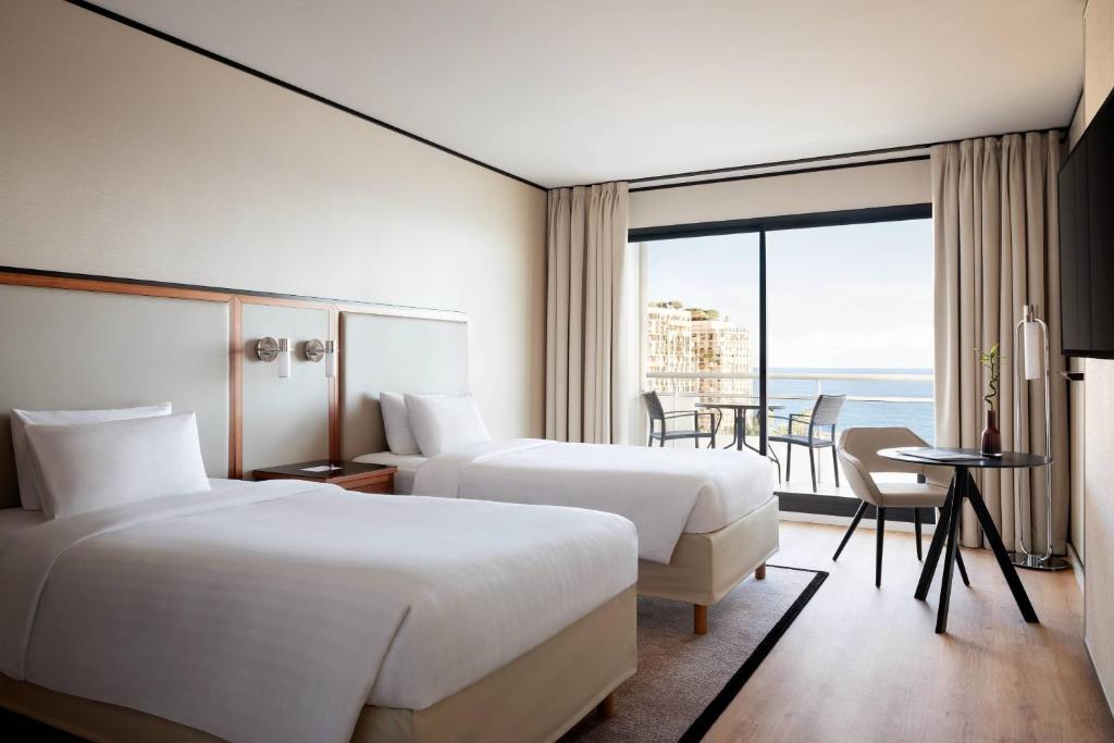 a hotel room with two beds and a balcony at Riviera Marriott Hotel La Porte De Monaco in Cap d'Ail