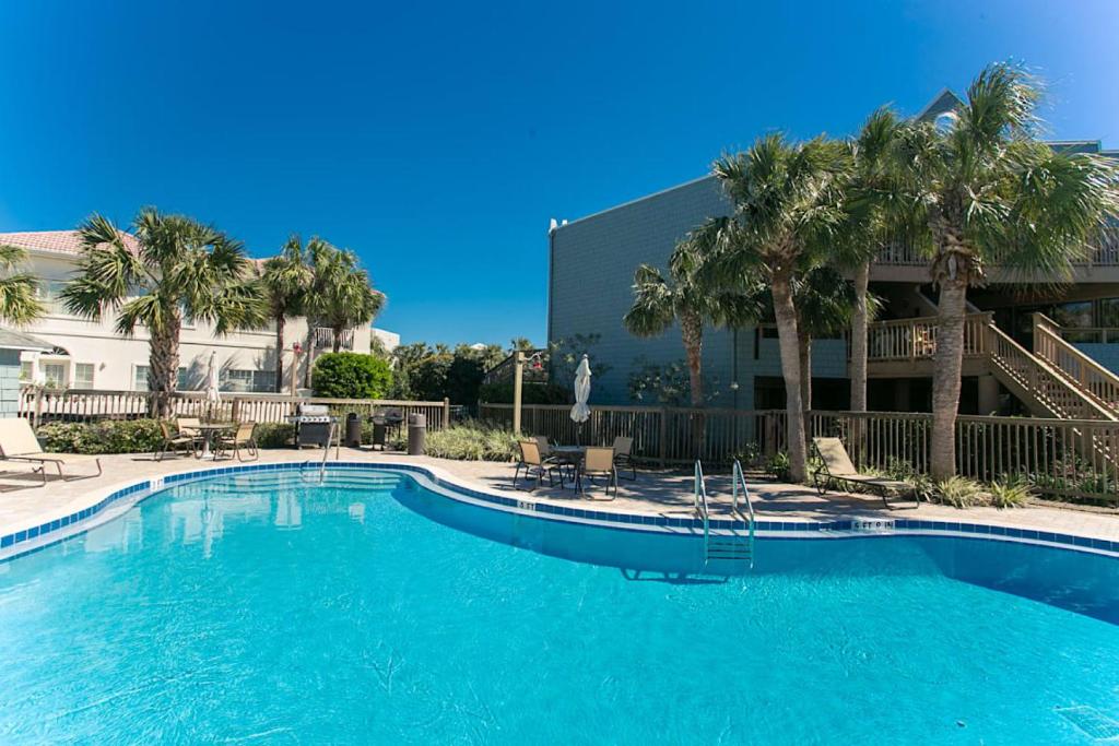 a large swimming pool with palm trees and a building at St Augustine Beach Luxury Resort Condo in Saint Augustine