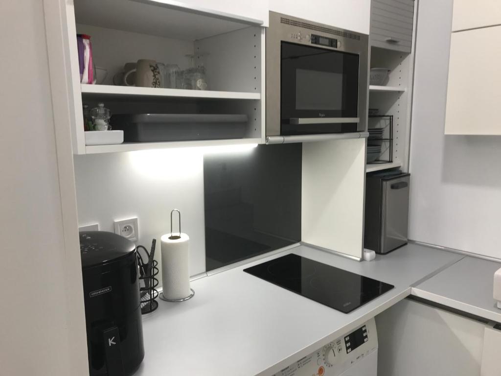 a white kitchen with a microwave and a refrigerator at 6 Next To Paris in Montreuil