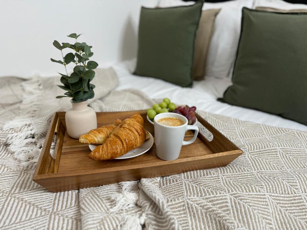 a tray with croissants and a cup of coffee on a bed at Central City Two-Bedroom in Swindon