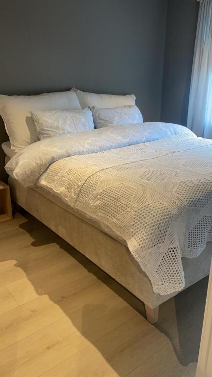 a bed with white sheets and pillows in a room at Leilighet midt i sentrum av vakre Hattfjelldal in Hattfjelldal