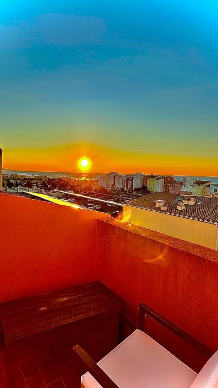 d'un balcon avec un banc offrant une vue sur le coucher du soleil. dans l'établissement Duplex vue mer - 150m de la plage, au Cap d'Agde