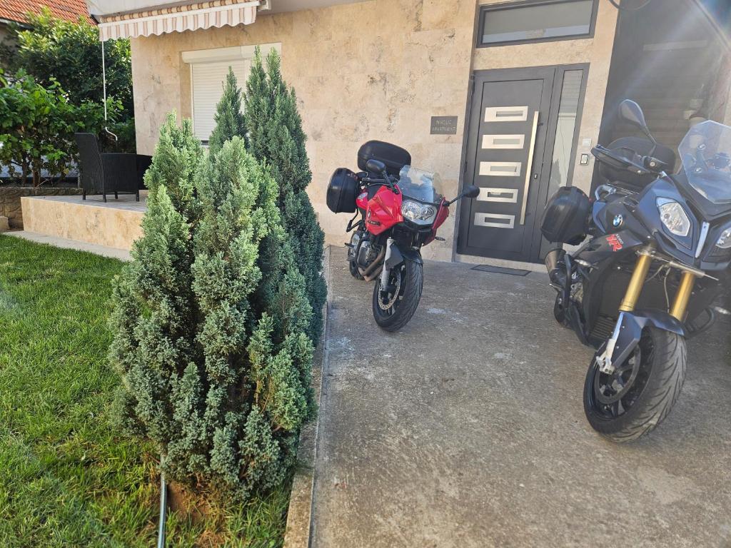 two motorcycles parked in a driveway next to a christmas tree at Nikolic Apartment in Leskovac