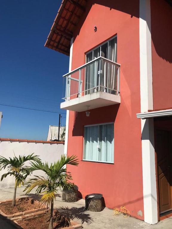 a red and white building with a balcony and palm trees at chalé vista para montanha in Penedo