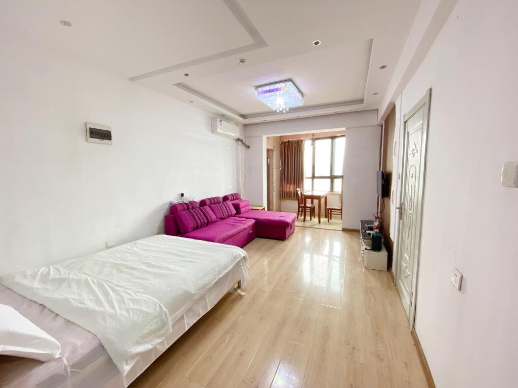 方远滨江国际 في هاربين: غرفة نوم بسرير واريكة ارجوانية