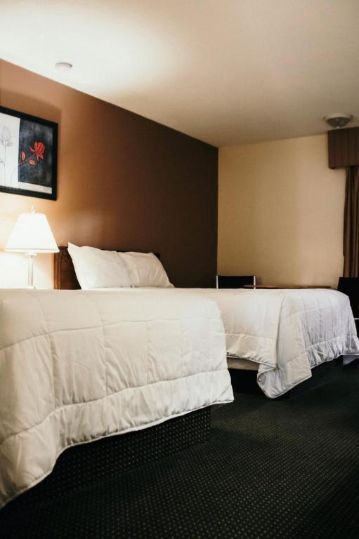 フォート・ネルソンにあるThe Fort Hotelの白いシーツが敷かれたベッドが2つあるホテルの部屋