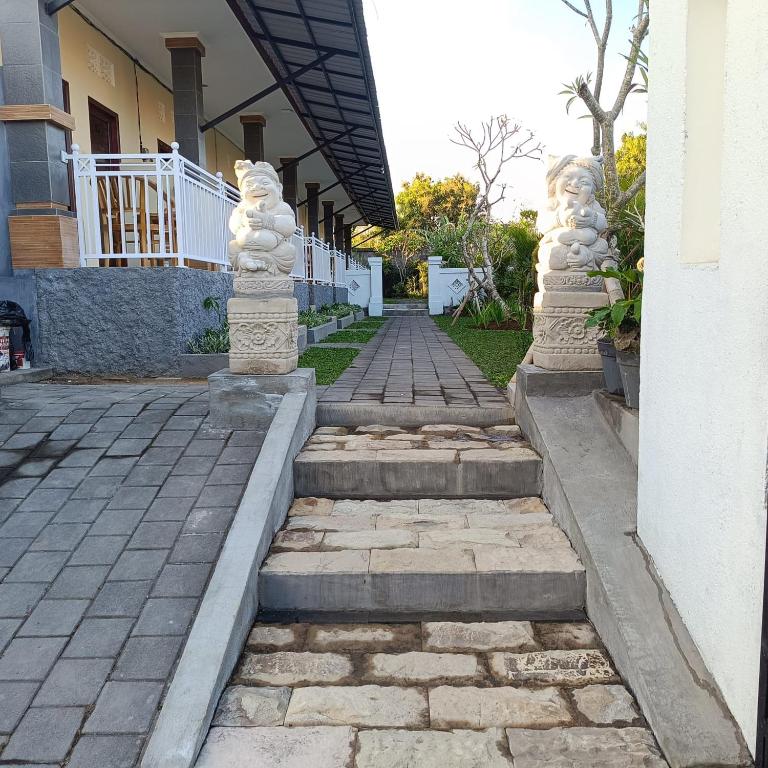 a walkway with stone statues next to a house at Prayoga homestay in Nusa Dua