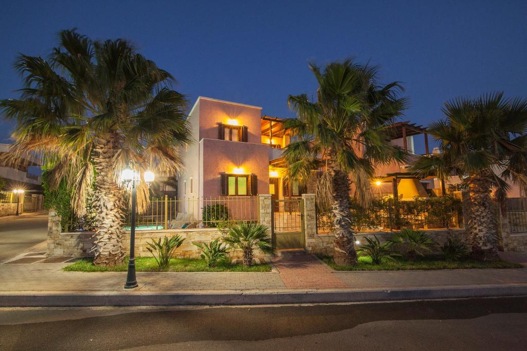 une maison avec des palmiers dans une rue la nuit dans l'établissement Pearls Of Crete - Holiday Residences, à Makry Gialos