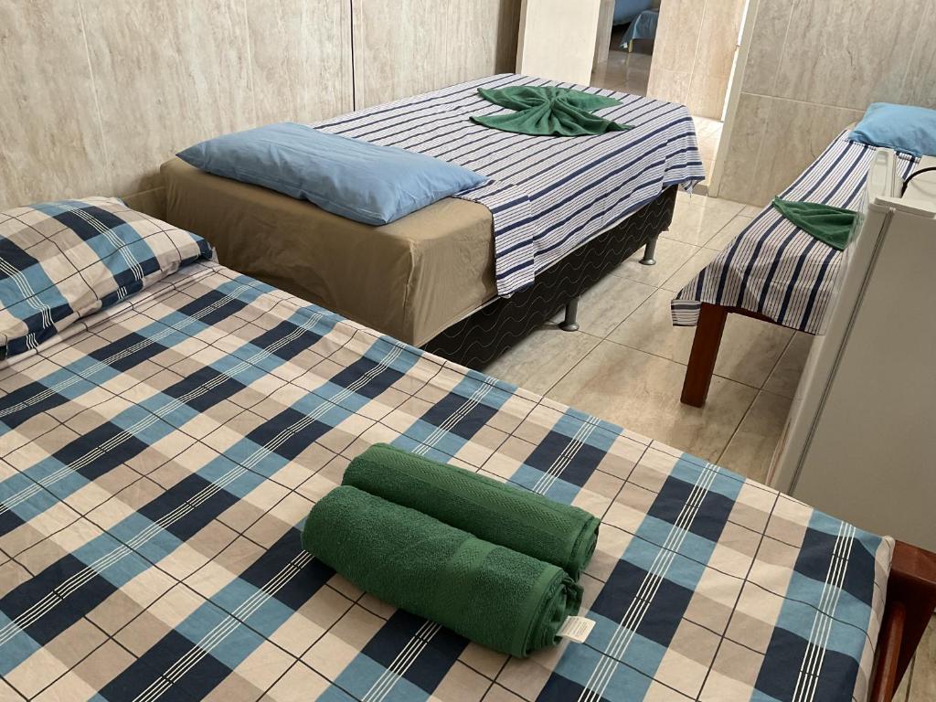 マセイオにあるPousada Pitangaのベッド2台と緑のオットマンが備わる部屋