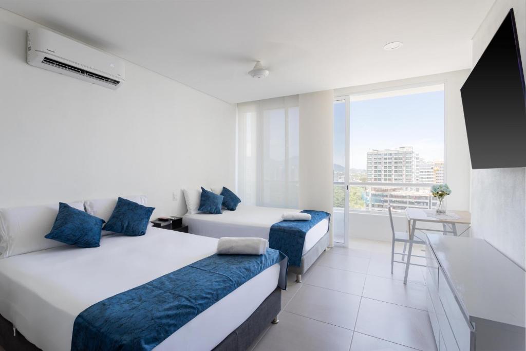 een hotelkamer met twee bedden en een televisie bij Condo Hotel Porto Horizonte in Santa Marta