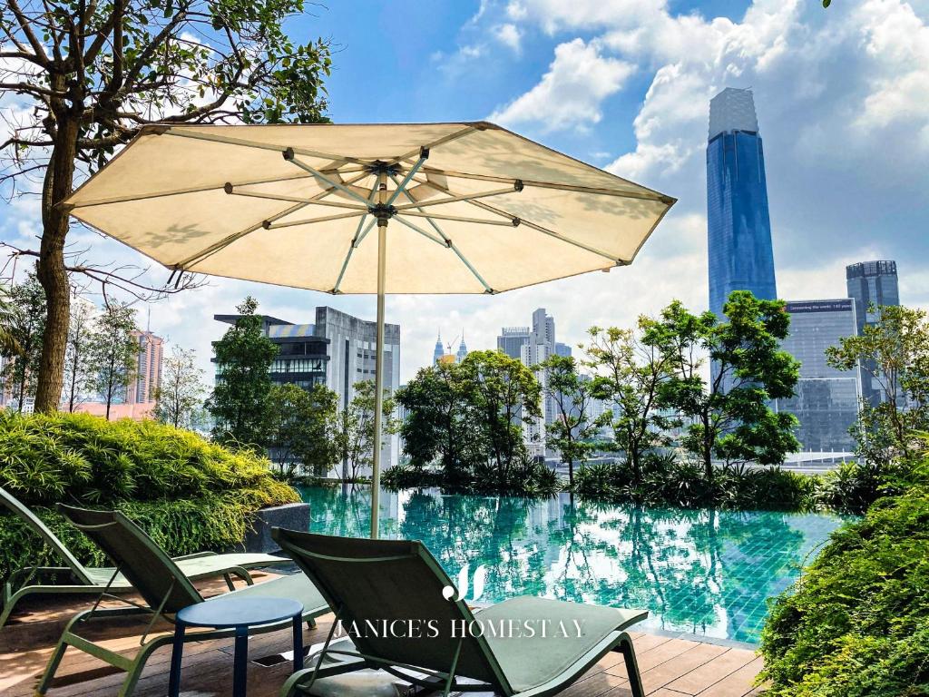 Una mesa y sillas con una sombrilla junto a una piscina. en Continew Residence by Janice's Homestay, en Kuala Lumpur