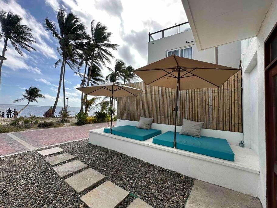 two benches with umbrellas on the side of a building at Two Bedroom Affordable Beach Front House in Boracay