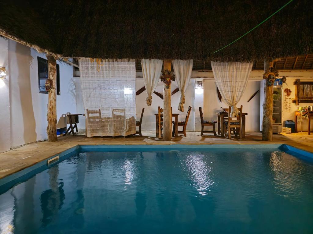 a swimming pool in a resort with a table and chairs at Villa Kumi in Nungwi