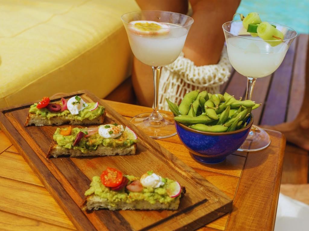 two plates of food and two glasses of drinks on a table at Secana Beachtown Resort & Residences in Canggu