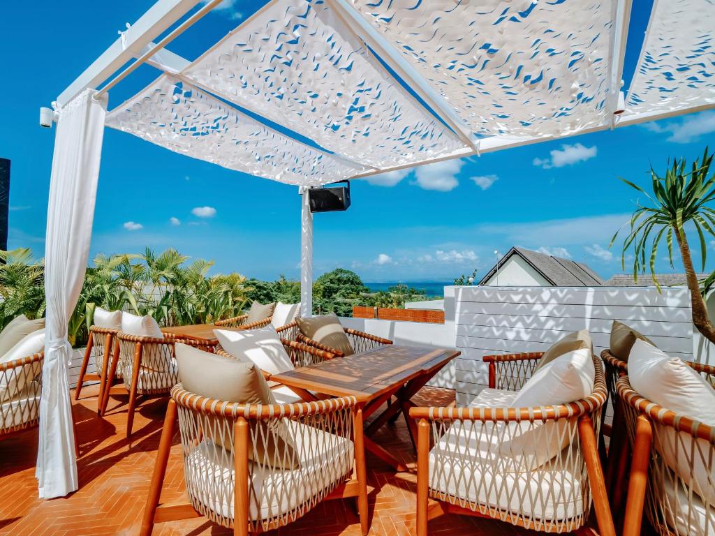 a patio with chairs and a table and an umbrella at Secana Beachtown Resort & Residences in Canggu