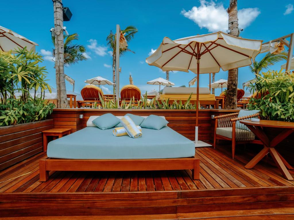 a bed on a deck with an umbrella at Secana Beachtown Resort & Residences in Canggu