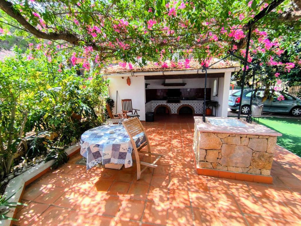 Un patio con una mesa y una chimenea con flores rosas. en Estudio Las Rotas, en Denia