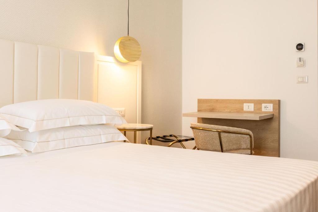 a bedroom with a white bed and a table at Mondello Glam Hotel & Terrace in Mondello