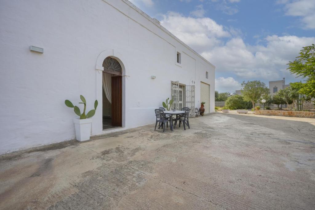 un patio de un edificio blanco con mesa y sillas en Casale Mba Graziudd, en Monopoli