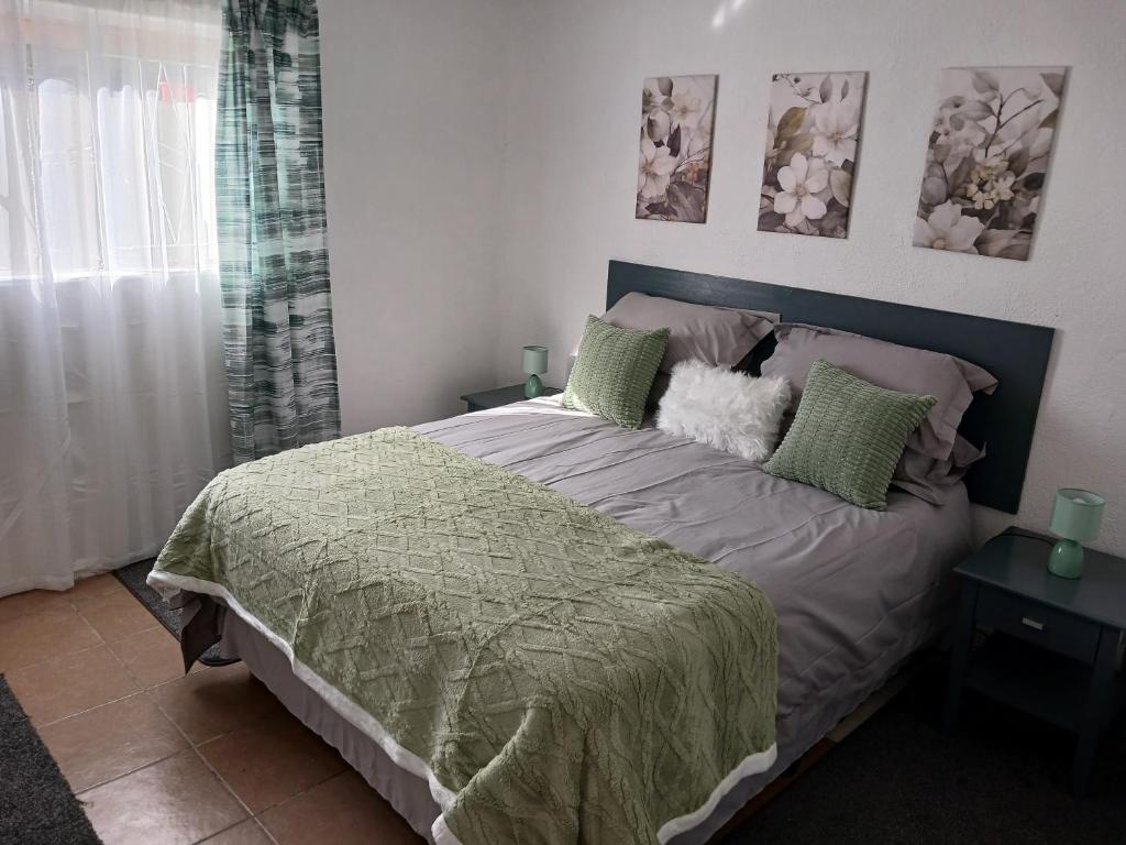a bedroom with a bed with a green comforter at The Garden Cottage in Polokwane