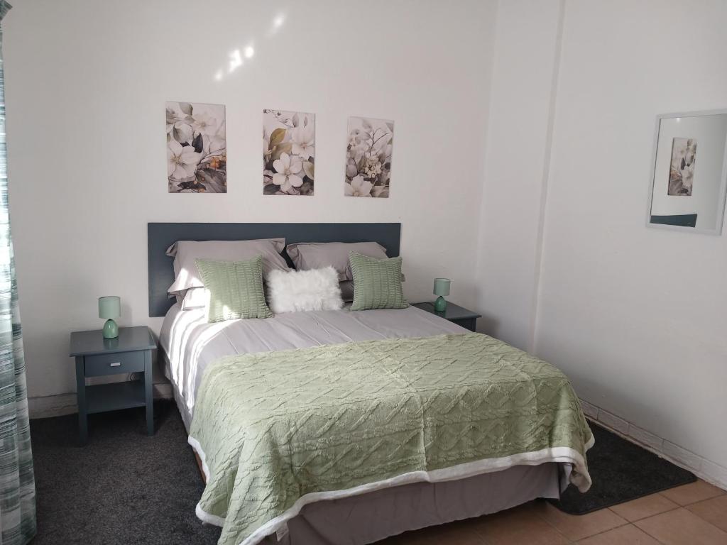 una camera da letto con un letto con due tavoli e due quadri sul muro di The Garden Cottage a Polokwane