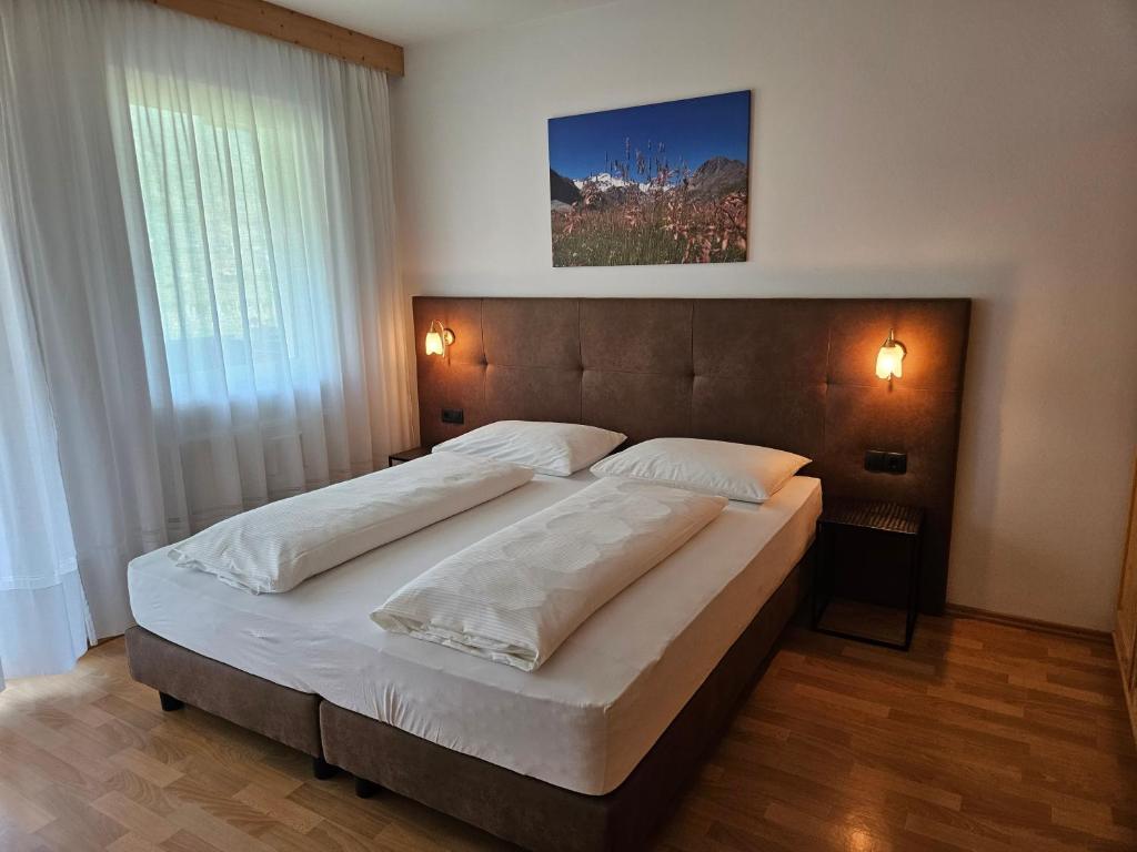 sypialnia z dużym łóżkiem z białą pościelą w obiekcie Residence Obstgarten w mieście Coldrano