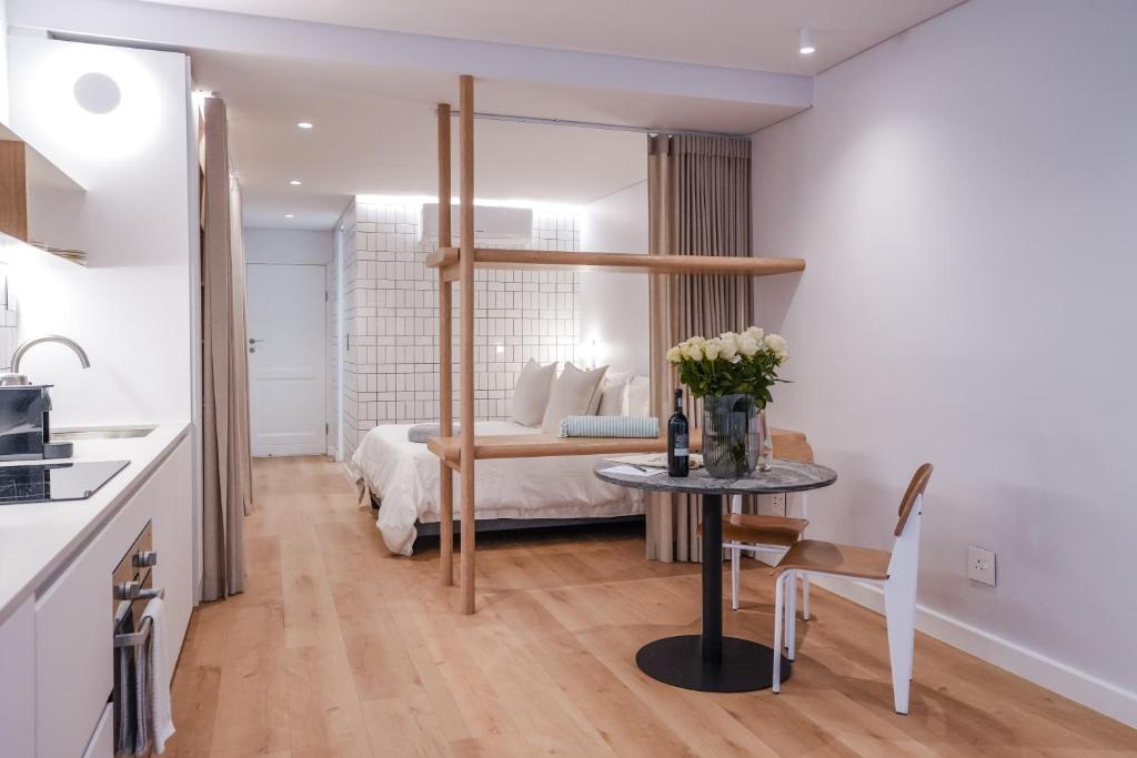 a bedroom with a bed and a table with flowers on it at Seaside 9 l Stylish Aparthotel in Three Anchor Bay in Cape Town