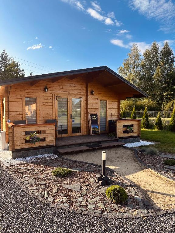 a log cabin with a porch and a house at LandsBy Apartments in Ostrów Warcki