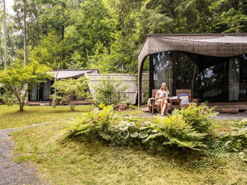 a woman sitting on a bench in a garden at Forest Camping Resort Blaguš in Sveti Jurij ob Ščavnici