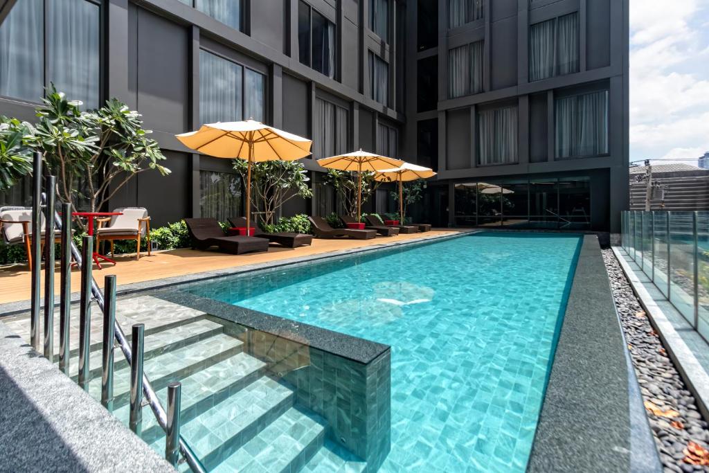 A rectangular outdoor pool sits in a landscaped courtyard between dark hotel buildings.