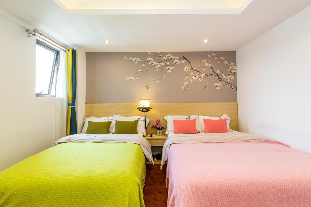 two beds in a room with yellow and pink at 桂林依庐居民宿 in Guilin