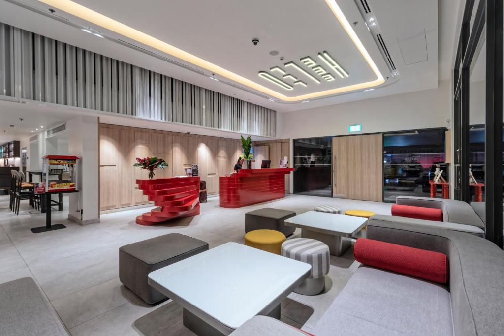 A contemporary lobby combines red reception desks with colourful modular seating and cafe-style tables.