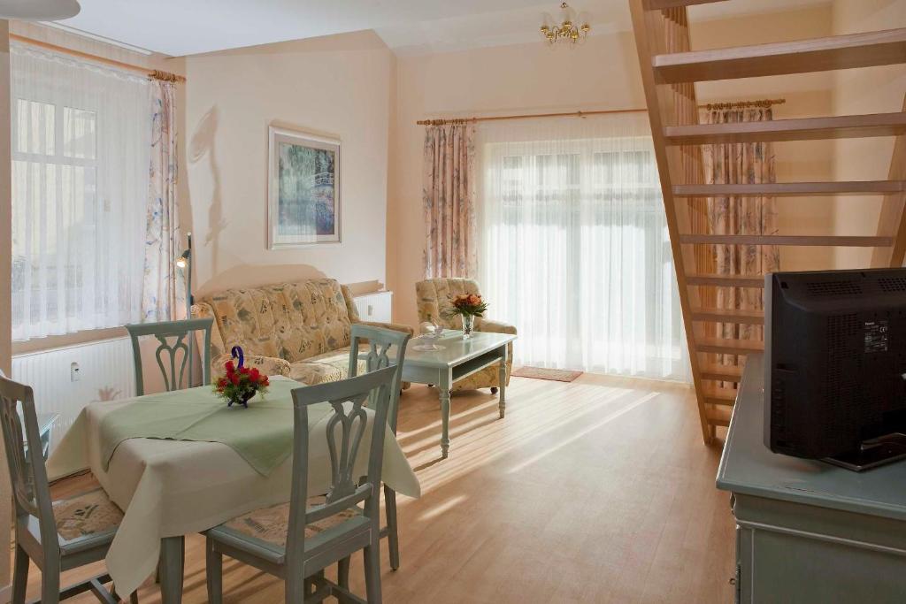 ein Wohnzimmer mit Tisch und Stühlen und einem Fernseher in der Unterkunft Fewo Rosenhof 13 in Kühlungsborn