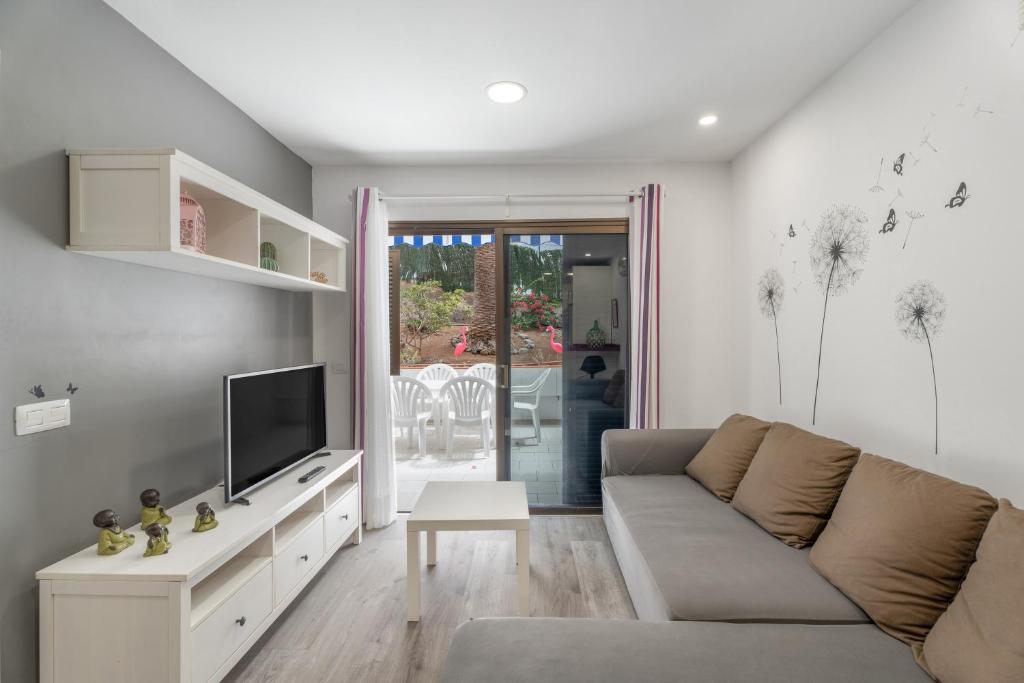 Una sala de estar con un sofá y un televisor. en Apto Jardin del Sol Beach, en Puerto de Santiago