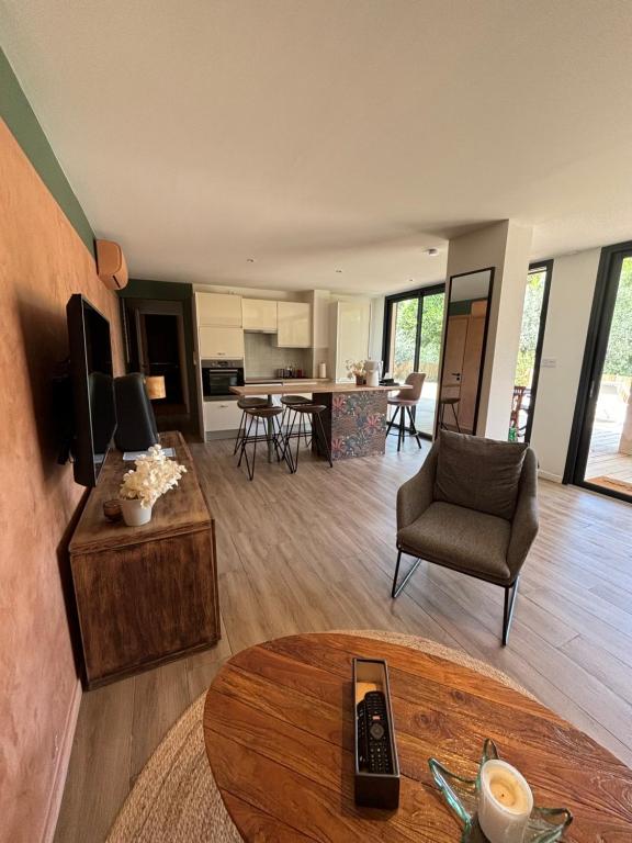 un salon avec une télévision et une table dans l'établissement Adorable Appartement de 60 m2 avec terrasse privée de 100m2 -lumineux - calme et verdure à 10 min de la mer, à Cagnes-sur-Mer
