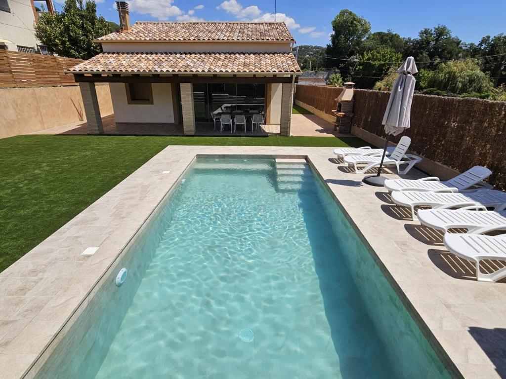 a swimming pool with chairs and an umbrella at Utopia in Puigventos