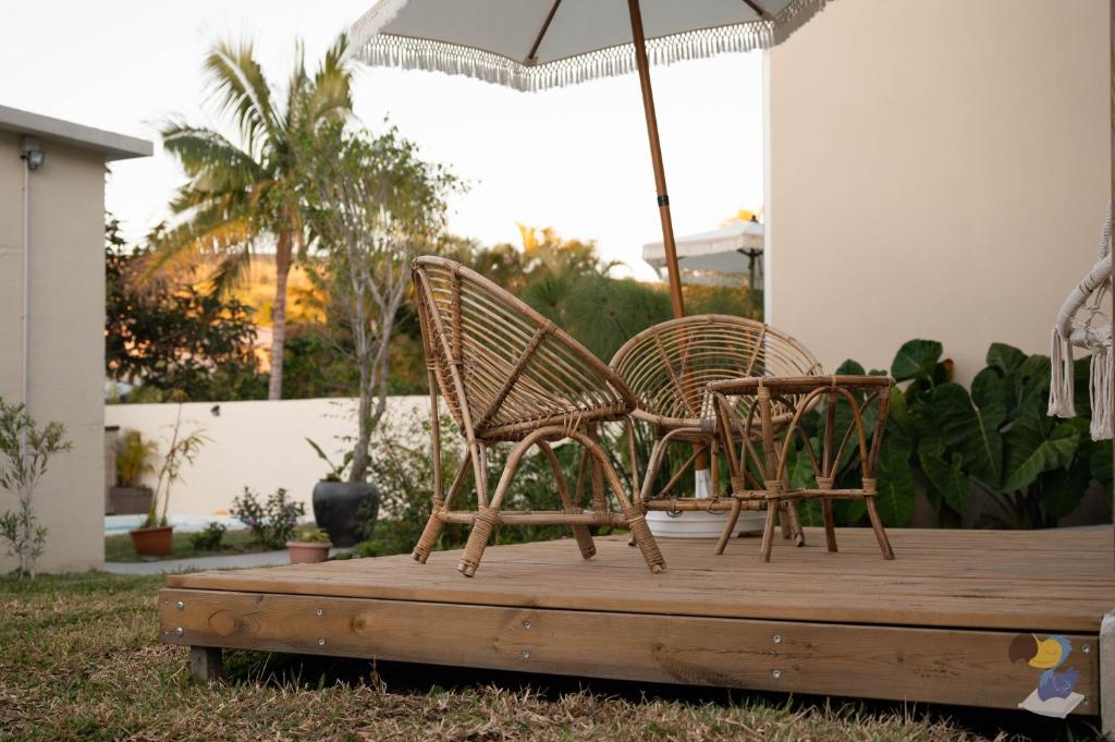 two chairs sitting on a deck under an umbrella at L'oasis - Lodges 3 étoiles - DODOTERLA in Le Onzième