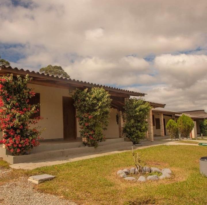 a house with two flowering bushes in front of it at Vinha dos Lagos Hotel in Rancho Queimado