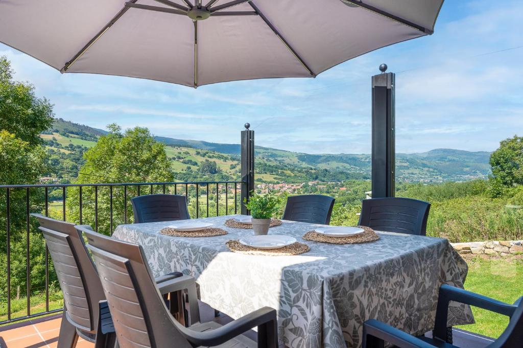 a table with chairs and an umbrella on a balcony at La Casuca de Barcena in Bárcena