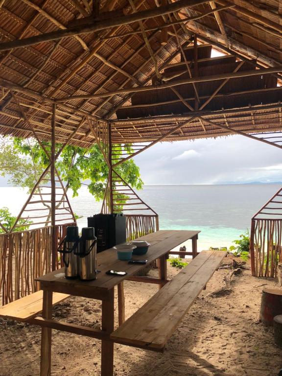 a picnic table on the beach with the ocean in the background at Frits Homestay in Kri
