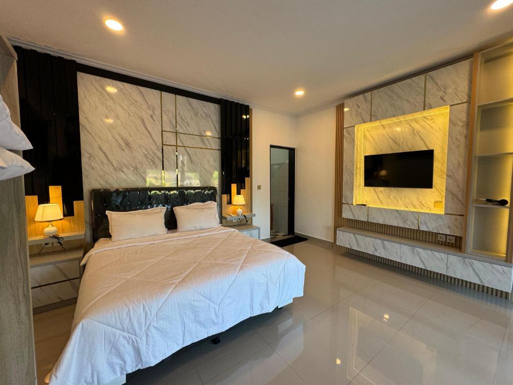 een slaapkamer met een groot bed en een flatscreen-tv bij Gecko Villa in Lovina