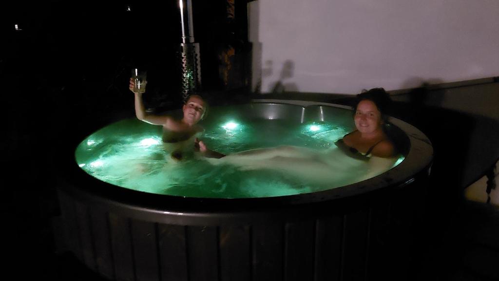 Due donne in una vasca idromassaggio con un bicchiere di vino di Cottage Zawoja z Jacuzzi a Zawoja