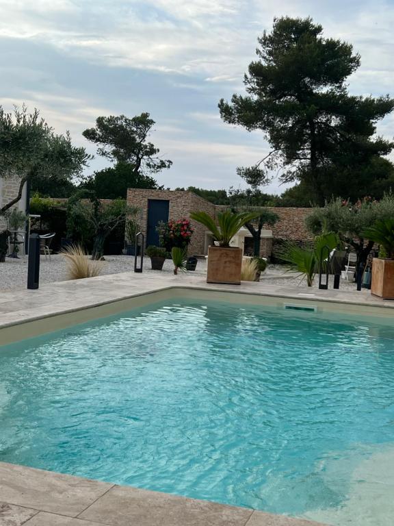 une piscine avec de l'eau bleue dans une cour dans l'établissement Maison, hauteur de Nimes, à Mas-de-Ponge