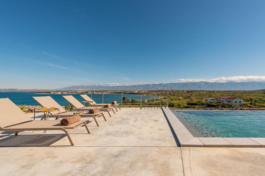 a row of lounge chairs next to a swimming pool at Talaferna Residences - luxury villas in Povljana